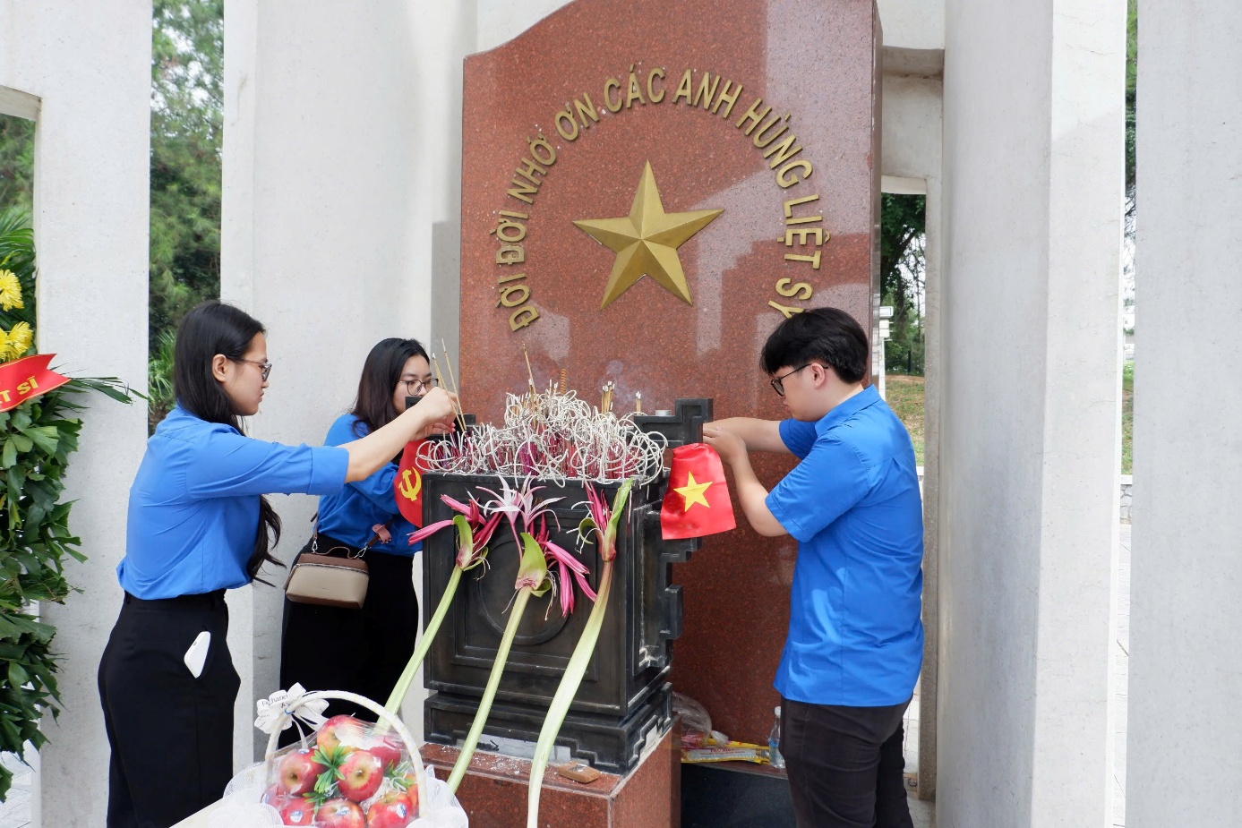 A group of people putting flowers on a monument

Description automatically generated